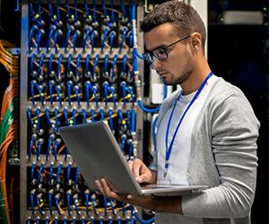 Network administrator using a laptop in the server room